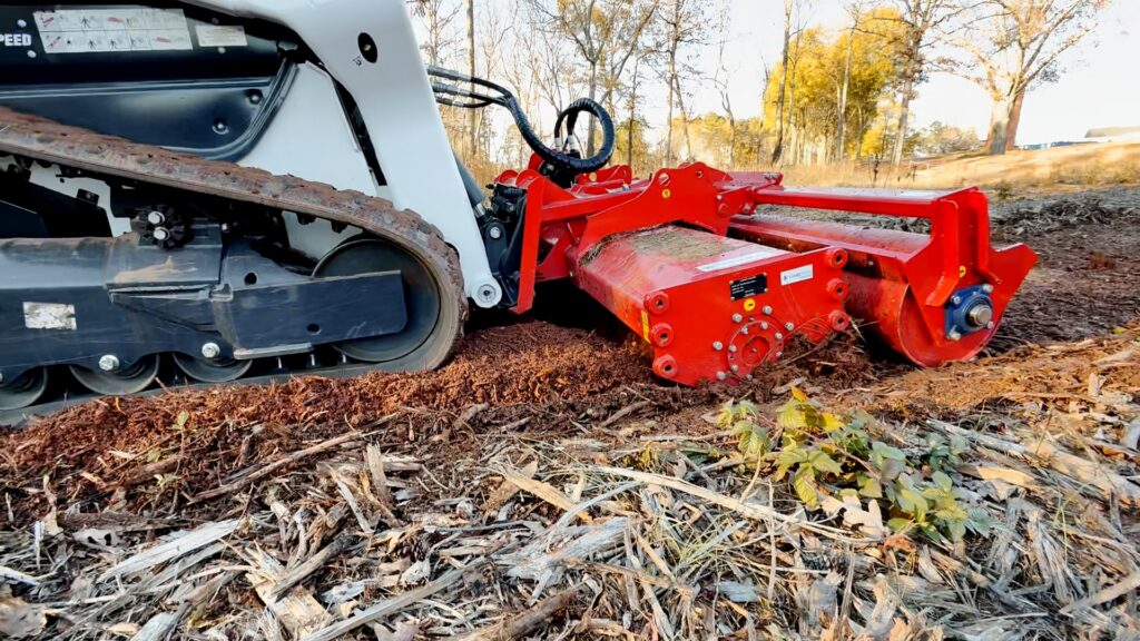 Carpet Mulching Close-up of a Coneteks Subsoil Mulcher in a thick layer of wood chips and debris after forestry mulching, showing the difficulty of secondary processing. Removing larger trees and then using only our attachment is a better way to clear your land.