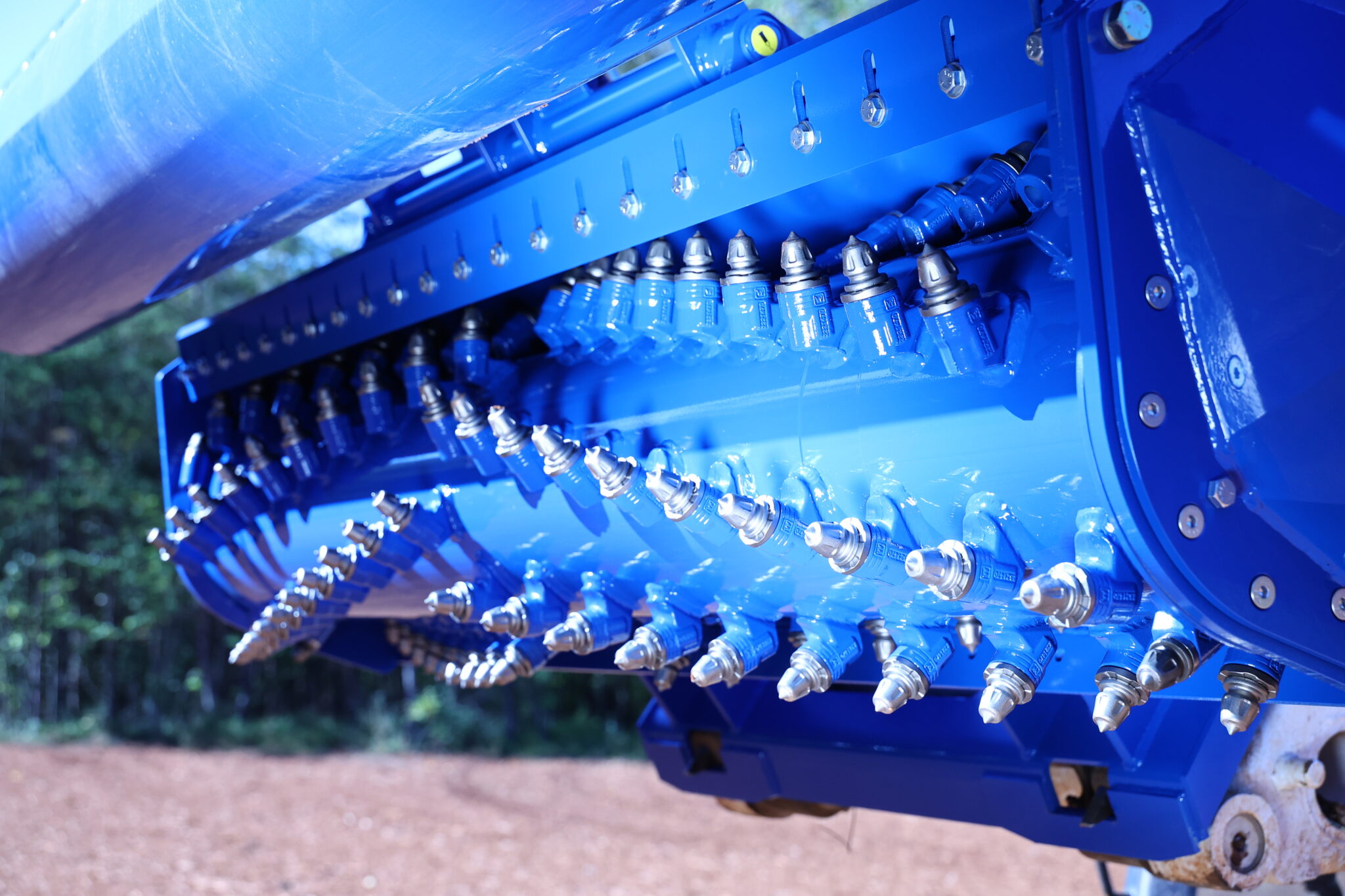 A Coneteks subsoil mulcher with its rotor lifted in the air, showing the angled forestry teeth and the front roller used for holding down loose material during mulching and for compacting and conditioning soil while back dragging.